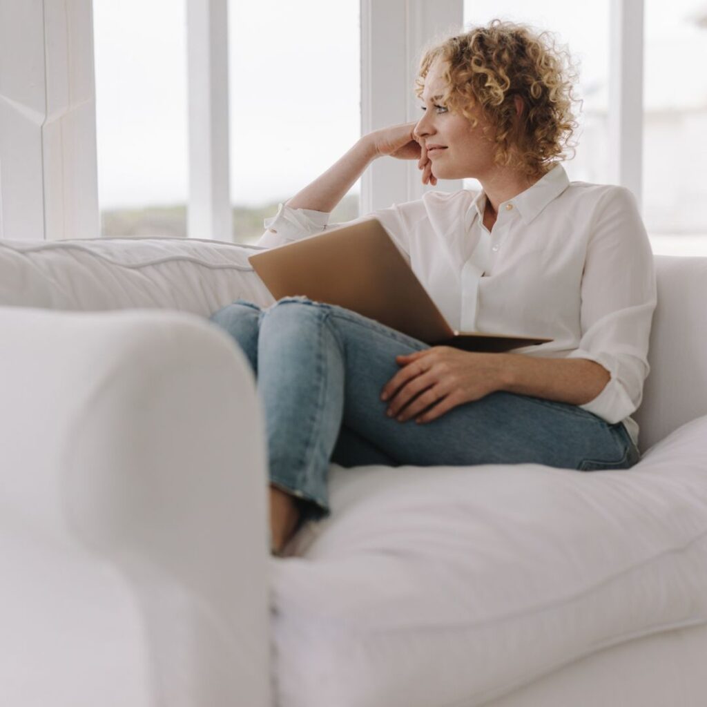 woman sitting on couch looking out window