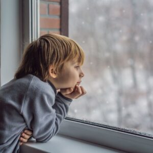 kid looks out window to snow outside 