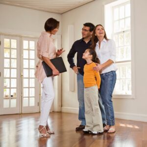 realtor stands with family in room with windows 